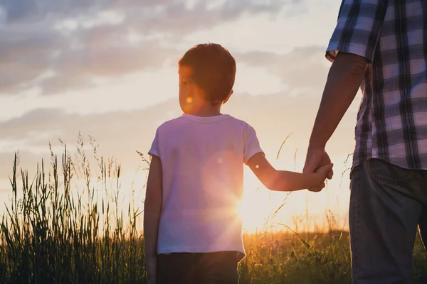 Vader en zoon spelen in het park bij de zonsondergang keer. — Stockfoto