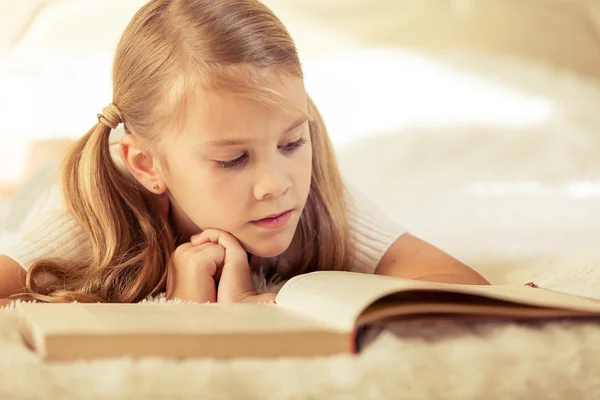 Little girl lying on the bed and reading a book — Stock Photo, Image