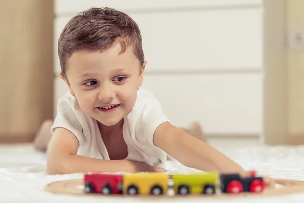 Adorable little boy playing with toys lying on the floor. — Stock Photo, Image