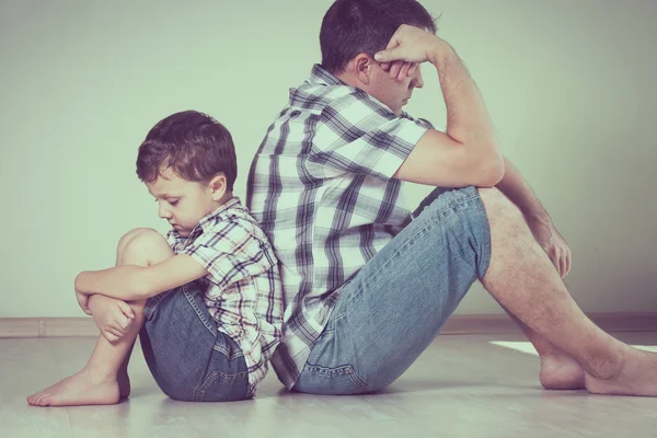 Fils triste et son père assis sur le sol dans la chambre à l'heure du jour — Photo