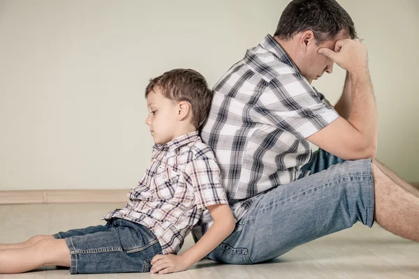 悲伤的儿子和他的爸爸坐在房间的地板上，在一天时间 — 图库照片