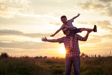 Baba ve oğul günbatımı anda parkta oynamak.