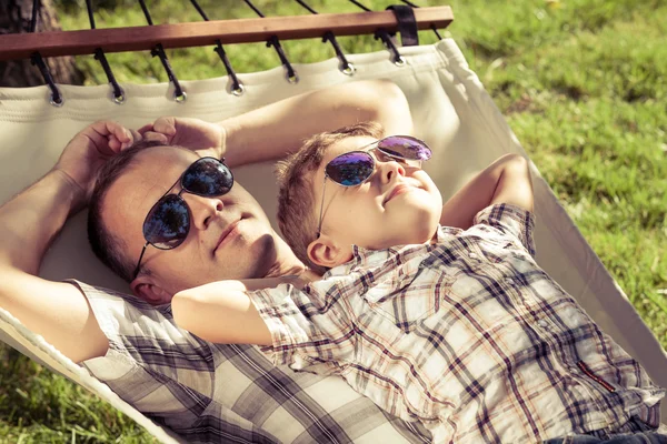 Father and son lying on hammock in the garden. — Stock Photo, Image