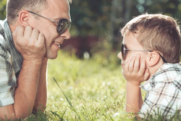 Pai e filho deitados perto da árvore no jardim . — Fotografia de Stock