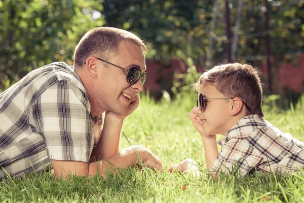 Father and son lying near the tree in the garden. — Stock Photo, Image