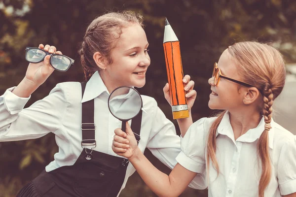 Crianças de escola jovens sorridentes em um uniforme escolar contra uma árvore — Fotografia de Stock