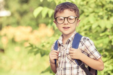 Bir ağaçta karşı okul üniformalı genç okul çocuk gülümseyen