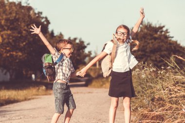 Bir ağaç karşı okul üniformalı genç okul çocukları gülümseyen