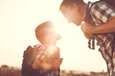 Baba ve oğul günbatımı anda parkta oynamak.