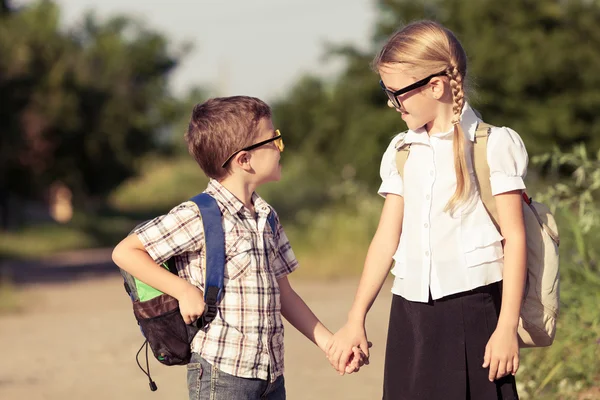 Bir ağaç karşı okul üniformalı genç okul çocukları gülümseyen