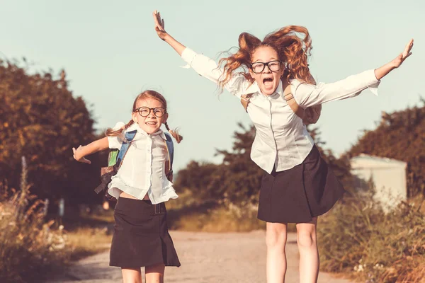 Des jeunes écolières souriantes en uniforme scolaire contre un arbre dans — Photo