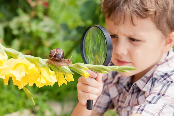 Glad liten pojke spelar i parken med snigel på dagarna. — Stockfoto