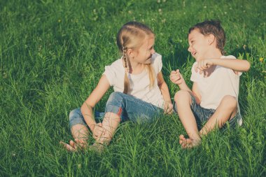 İki mutlu çocuk ağacın yanında çim üzerinde gün oyun.