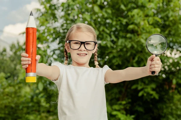 Sonriente niño pequeño en un uniforme de pie contra un árbol en el — Foto de Stock