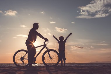 Baba ve oğul sahilde günbatımı anda oynamak.