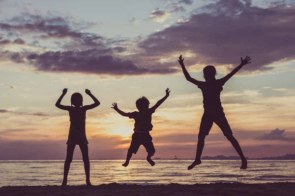 Glückliche Kinder spielen am Strand bei Sonnenuntergang. — Stockfoto