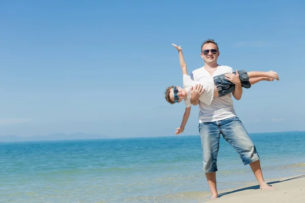 Vader en zoon spelen op het strand op het moment van de dag. — Stockfoto