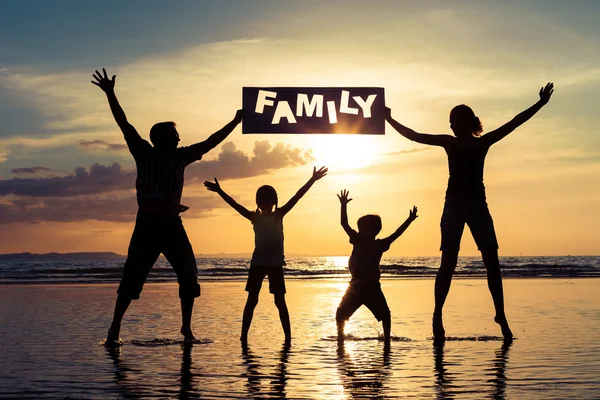 Silueta de familia feliz que de pie en la playa en los soles — Foto de Stock