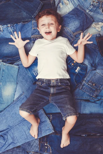 Schattige kleine jongen liggend op de achtergrond-jeans. — Stockfoto