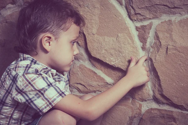 Smutný malý chlapec seděl u zdi — Stock fotografie