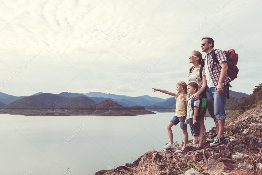Happy family standing near the lake at the day time.