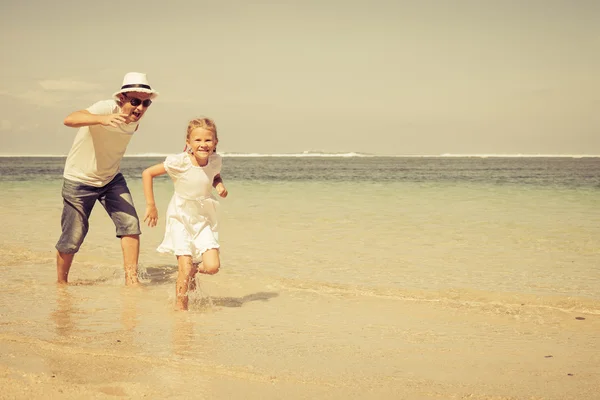 Far och dotter kör på stranden på dagarna — Stockfoto