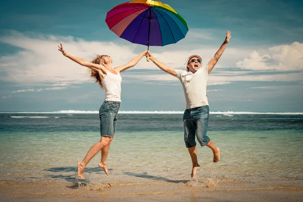 Feliz pareja saltando en la playa durante el día — Foto de Stock