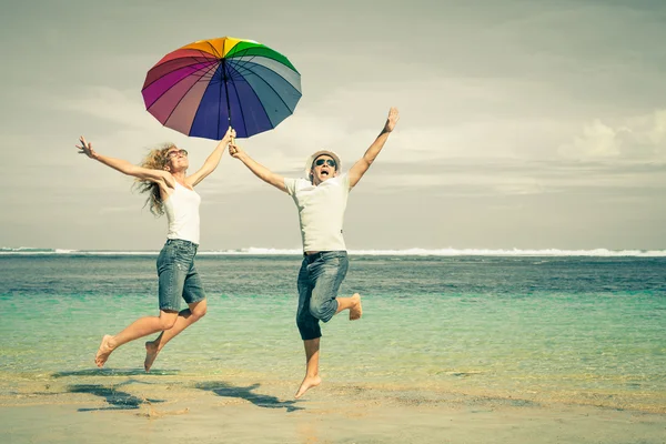 Couple heureux sautant sur la plage à l'heure du jour — Photo