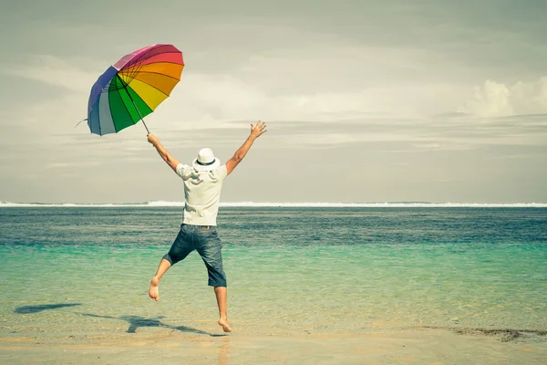 Un homme heureux saute par-dessus la mer. Plage de sable le jour . — Photo