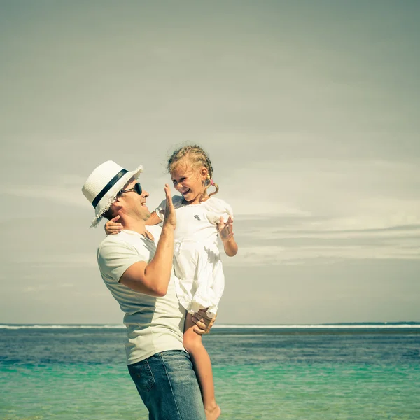 Far och dotter spelar på stranden på dagarna — Stockfoto