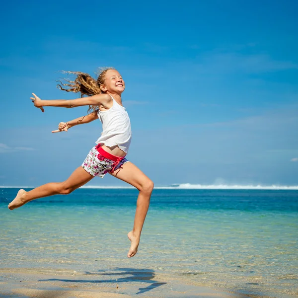 Tiener meisje springen op het strand van blauwe zee kust in zomer vaca — Stockfoto