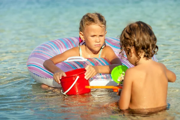 Kleine Jungen und Mädchen spielen tagsüber am Strand — Stockfoto