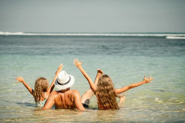 Padre y dos hijas sentadas en la playa durante el día —  Fotos de Stock