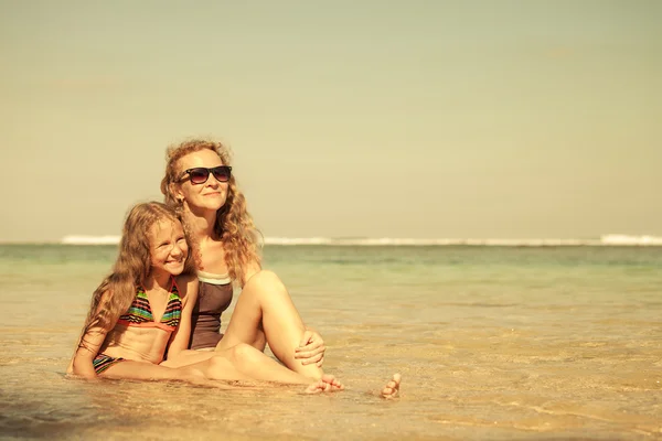 Madre e hija sentadas en la playa durante el día — Foto de Stock