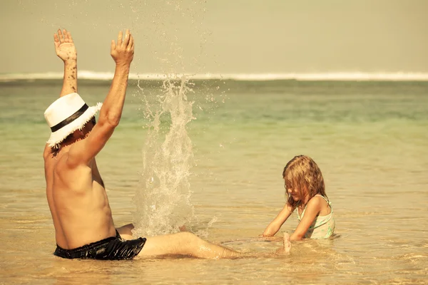 Far och dotter spelar på stranden på dagarna — Stockfoto