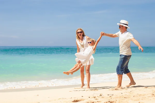 Счастливая семья, играющая на пляже днем — стоковое фото