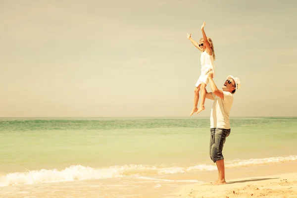 Far och dotter spelar på stranden på dagarna — Stockfoto