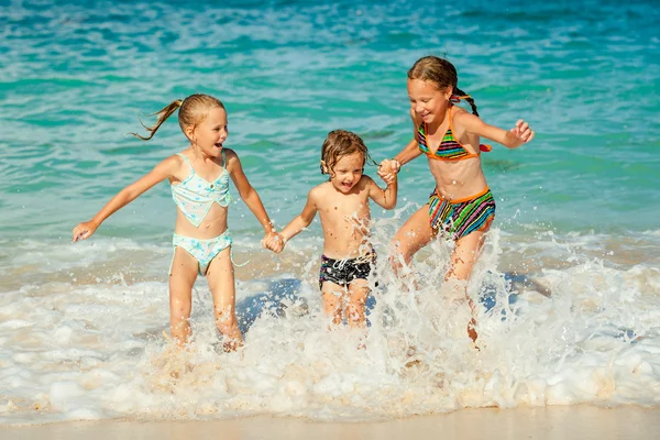 Glückliche Kinder, die tagsüber am Strand spielen — Stockfoto