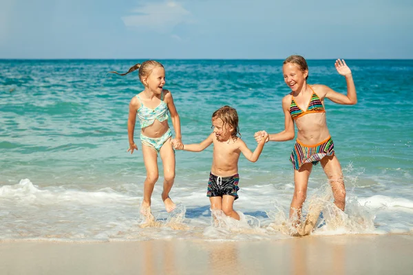 Niños felices jugando en la playa durante el día — Foto de Stock