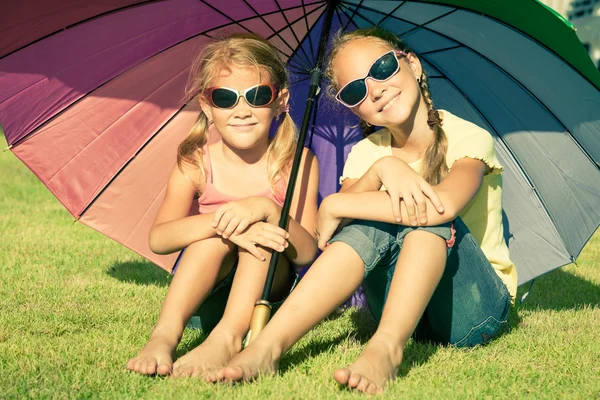 Porträt von zwei glücklichen Schwestern, die am Tag der Geburt auf dem Rasen sitzen. — Stockfoto