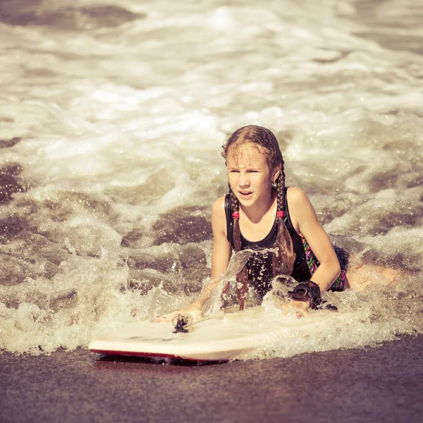 Szczęśliwa dziewczyna z deską surfingową na plaży w czasie dnia — Zdjęcie stockowe