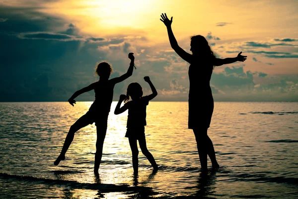 Silueta de familia feliz que juega en la playa al atardecer — Foto de Stock