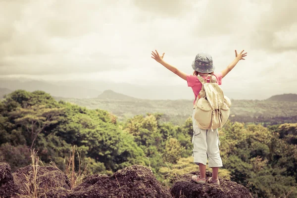 Menina com uma mochila em pé no topo de uma montanha — Fotografia de Stock