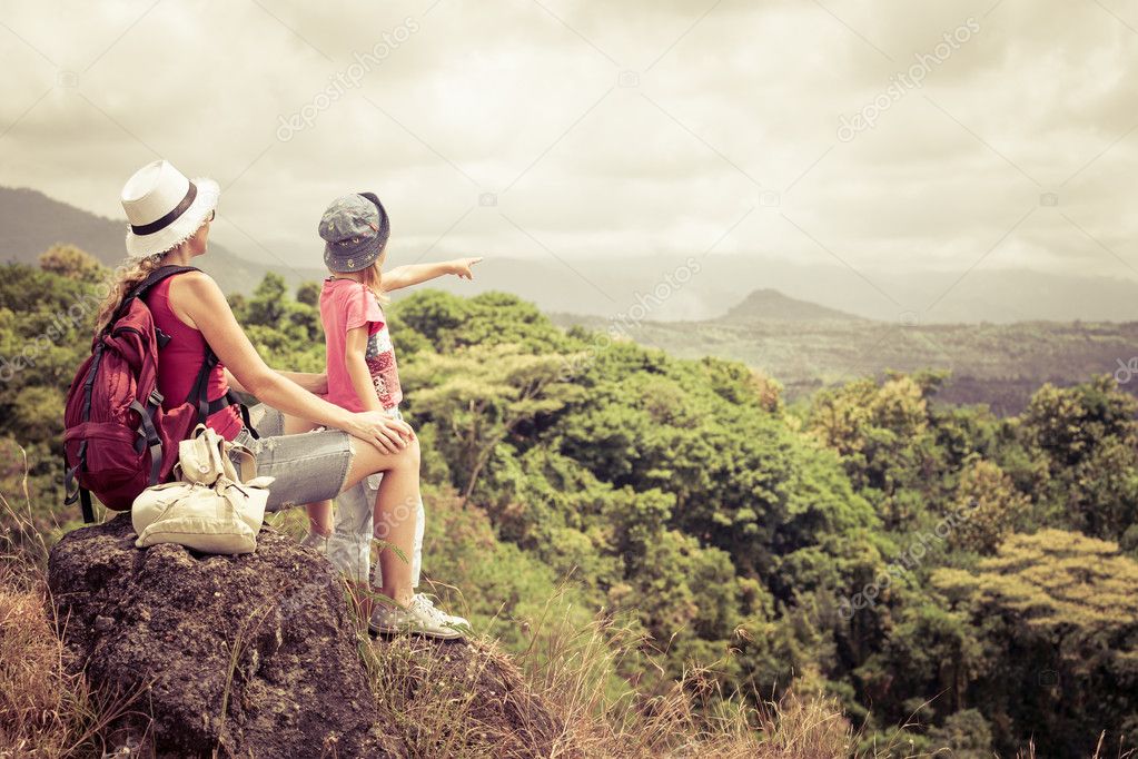 mother and daughter with backpack sitting on the footpath in the