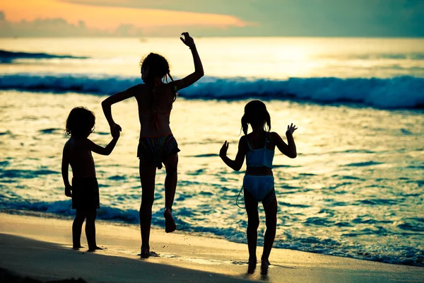 Niños felices jugando en la playa al amanecer —  Fotos de Stock