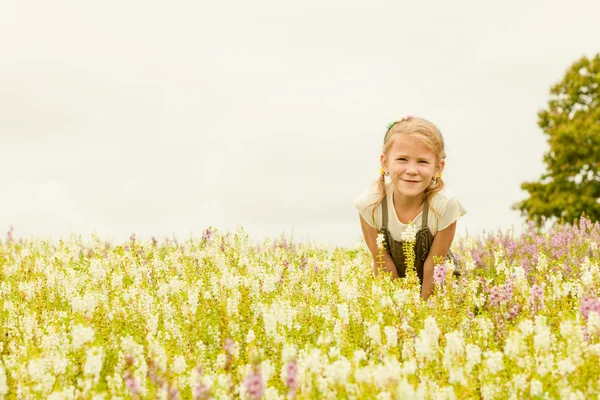 Glückliches kleines Kind im grünen Blumenfeld. — Stockfoto