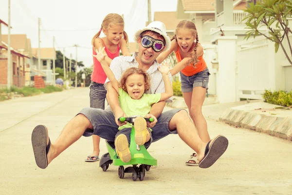 Pai e filhos brincando perto de uma casa no dia Fotos De Bancos De Imagens