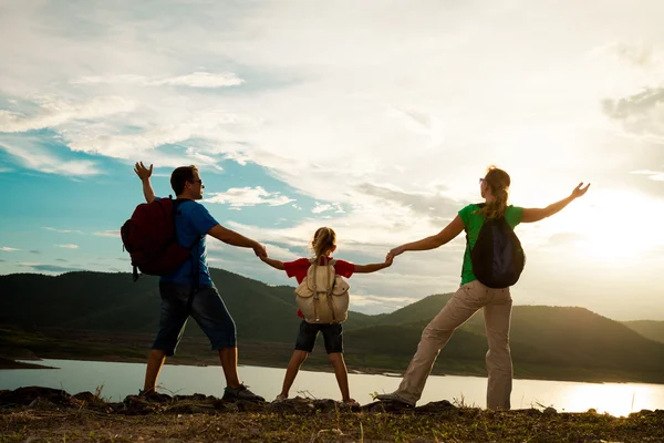 Father, mother and daughter standing on the coast of lake at the — Stock Photo, Image