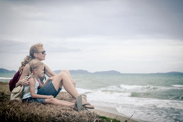 Glückliche Familie sitzt tagsüber am Strand. — Stockfoto