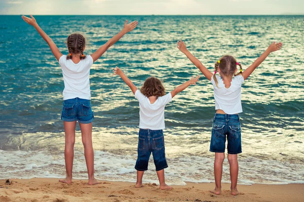 Tre glada barn stående på stranden — Stockfoto